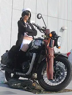 Girls und Panzer cosplayers take photos in the itasha exhibition area of the doujinshi sale.