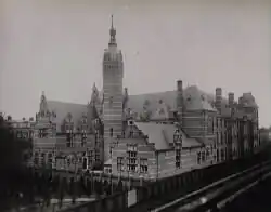 A large ornate, gated building with a large central tower backdropped by a hazy sky