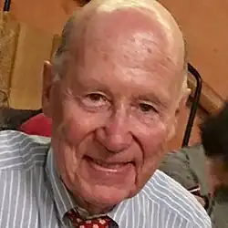 Clean-shaven, smiling, elderly man, with short hair and receding hairline.
