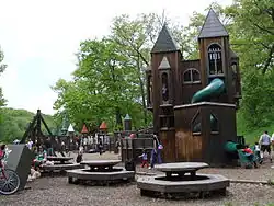 dark brown wooden structure resembling a castle with circular tables in front