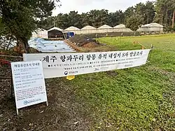 A fenced off area with white tents and tarps covering the earth
