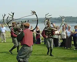 Three men carrying reindeer horns dancing