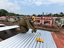 A man repairs a roof on a damaged house.