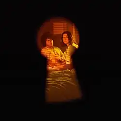 Selena Gomez and Benny Blanco lying in bed viewed through a keyhole