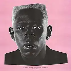 Monochrome photo of Tyler, the Creator staring at the camera, surrounded by a pink background. The words "All songs written, produced and arranged by Tyler Okonma" are visible on the bottom.