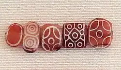 Indian carnelian beads with white design, etched in white with an alkali through a heat process, imported to Susa in 2600–1700 BCE. Found in the tell of the Susa acropolis. Louvre Museum, reference Sb 17751.[80][81][82] These beads are identical with beads found in the Indus Civilization site of Dholavira.[83]