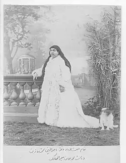 A black and white photograph of a woman with long dark hair, and a voluminous white dress.