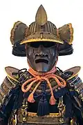 The fukigaeshi can be seen to both sides of the mabizashi (brim), and the shinobi-no-o (cord) secures the mengu (facial armour).