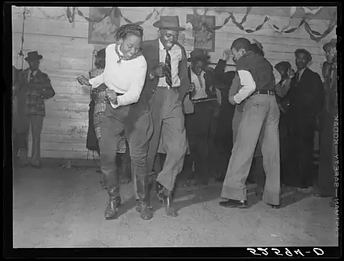 Social dance – dancers at a juke joint dance the Jitterbug, an early 20th century dance that would go on to influence swing, jive, and jazz dance.