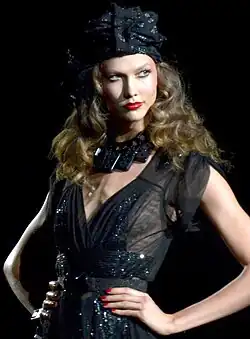 Karlie Kloss posing, wearing a black dress and chocker necklace