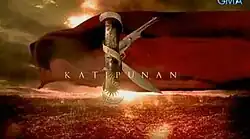 An image of an object forming the letter K, with a red fabric and skyline on the background. The series title is displayed on the center of the image.