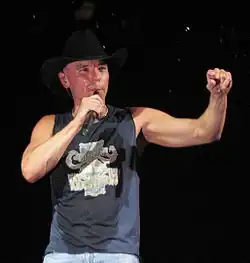 Kenny Chesney, singing with one arm extended and the other holding a microphone