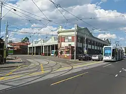 A photo of Kew tram depot. There is one C-class stabled and another C-class is passing the depot on Barkers Road.