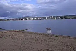 A metal sign erected on the sandy shores of the lake advises of the ban on water activity due to pollution