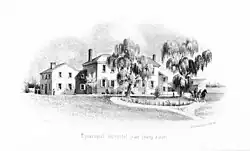 View of the driveway leading up to a large house with several outbuildings.".