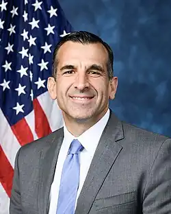 Official House portrait of Liccardo smiling in front of the U.S. flag, wearing a grey suit, white shirt, and blue tie.