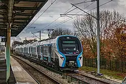A double-decker commuter eletric train on a station away from the platform.