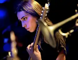 Musician Mali Obomsawin playing an electric bass guitar