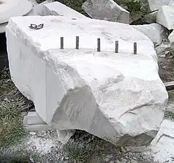 Using plug and feathers to split a block of marble from the quarry