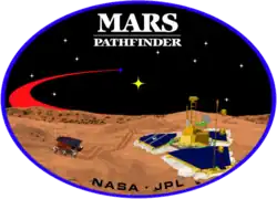 An image inside an oval, depicting two spacecraft, one a lander, and one a rover, on the surface of Mars. The words "Mars Pathfinder" are written on the top and the words "NASA · JPL" are written on the bottom.