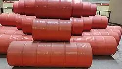Picture of a reddish sculpture made of oil drums.