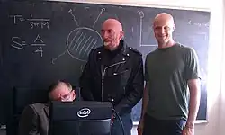 Physicists Michael Hartl, Kip Thorne, and Stephen Hawking in front of a blackboard with physics formulas and diagrams