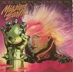 The Mission Earth iron fist with the text Mission Earth above it, next to Edgar Winter.