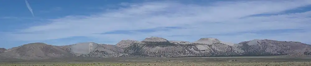 An overlapping series of gray domes with sharp peaks. Scrubland in foreground.