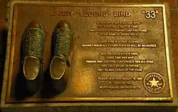 Bronzed shoes on a plaque with text describing Bird's basketball accomplishments
