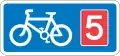 Rectangular, blue traffic sign with a white bicycle symbol and a red square with the number 5 in it.