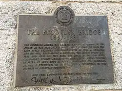 A plaque that certifies the Brooklyn Bridge as a New York City designated landmark