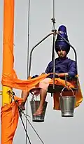 A Nihang Singh changing cloth of Nishan Sahib, Gurdwara Singh Shaheedan, Sohana, Mohali, Punjab, India
