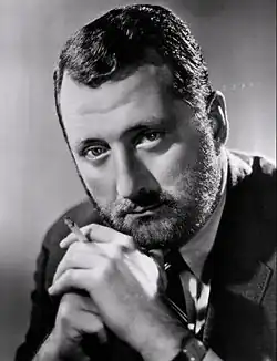 A bearded man holding a cigarette