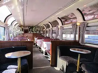 Glass windows curving up to ceiling above rows of tables