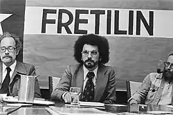 Men at a table in front of a flag with the word FRETILIN