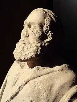Head and upper body of a statue depicting an old man with a large beard. Minimal damage includes a missing nose.