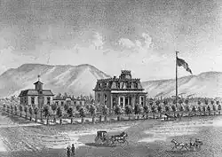 A black-and-white illustration showing the house on a large block surrounded by small trees, with a horse-drawn vehicle in front, large flag on a pole to the right, and mountains in the background