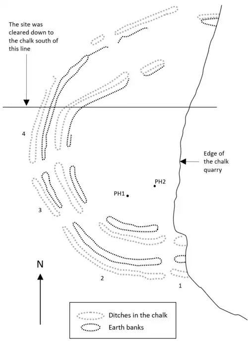 Approximately semi-circular arcs of ditches and banks, truncated by the edge of a quarry