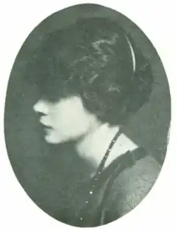 A young fair-skinned Black woman with dark hair, in profile, in an oval frame; she is wearing a strand of dark beads or stones