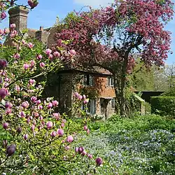 a view of a cottage in a garden full of flowers