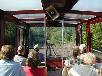The interior of a red tram car with many windows, full of people