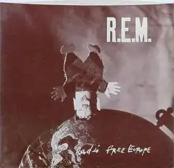 A sepia-toned photo of a toy doll standing on its head on a globe