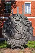 A sculpture of the emblem in front of a former military building in Kotovsk, Tambov Oblast.