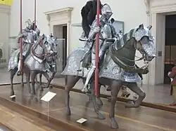 Three statues of riders and horses in armour