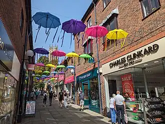 A display of colourful umbrellas with ribbons blowing in the wind hang above Coppergate Walk as part of Brollywalk.