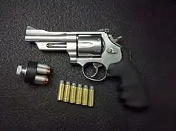 Left side view of a S&W Mountain Gun M625-6 .45 LC revolver, 4" barrel, with 250 gr. .45 Colt cartridges and a speedloader filled with home defense 250 gr. Underwood XTP