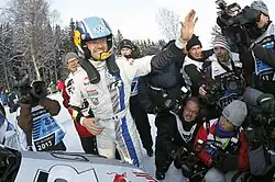 Sébastien Ogier with his arm raised surrounded by photographers at the 2013 Rally Sweden