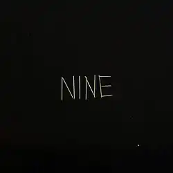 A black background with matchsticks spelling out "NINE" on it
