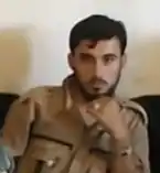 A man with a short beard, clothed in a khaki uniform