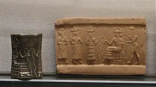 Akkadian cylinder seal depicting the enthroned Enki accompanied by a Lahmu holding a gate-post, and his two faced vizier, who introduces a personal goddess leading the owner of the seal.